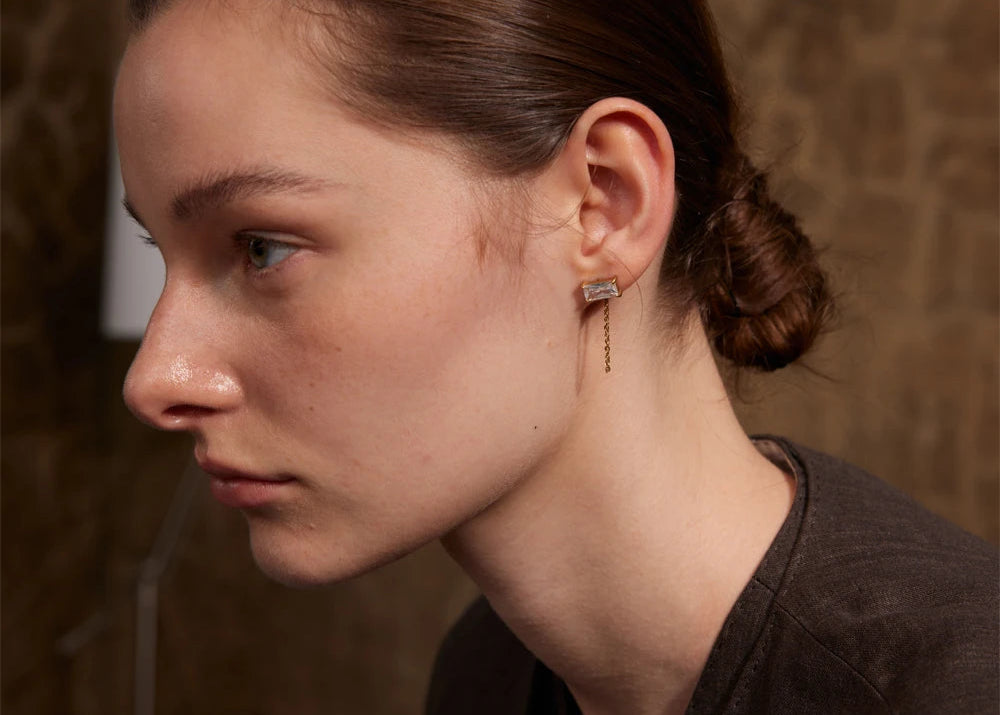 Fashion-forward earrings with a unique chain detail worn by a stylish model.