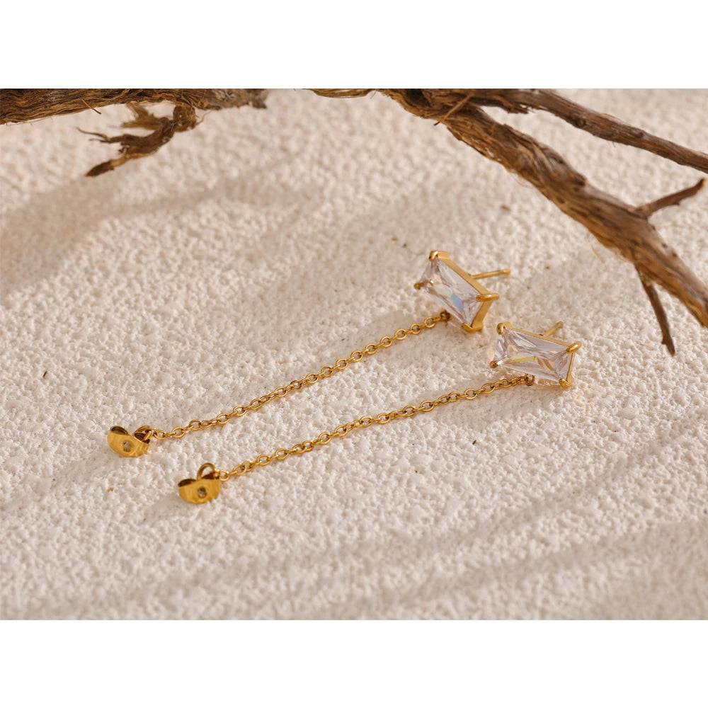 Close-up of gold and crystal earrings with intricate chain details for a sleek aesthetic.