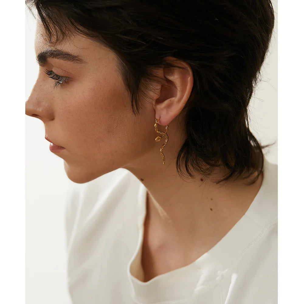 A model wearing elegant snake-shaped earrings, showcasing a bold and luxurious design